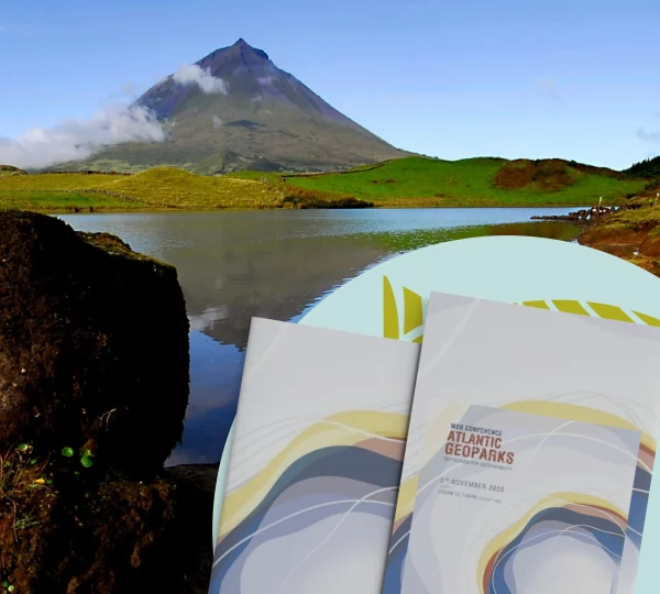 Under a cloudy sky, the tall volcano is surrounded by lush greenery and a serene lake, capturing the essence of the Atlantic Geoparks Route. In the foreground, brochures featuring wavy designs and text about these routes dated November 2020 are on display.